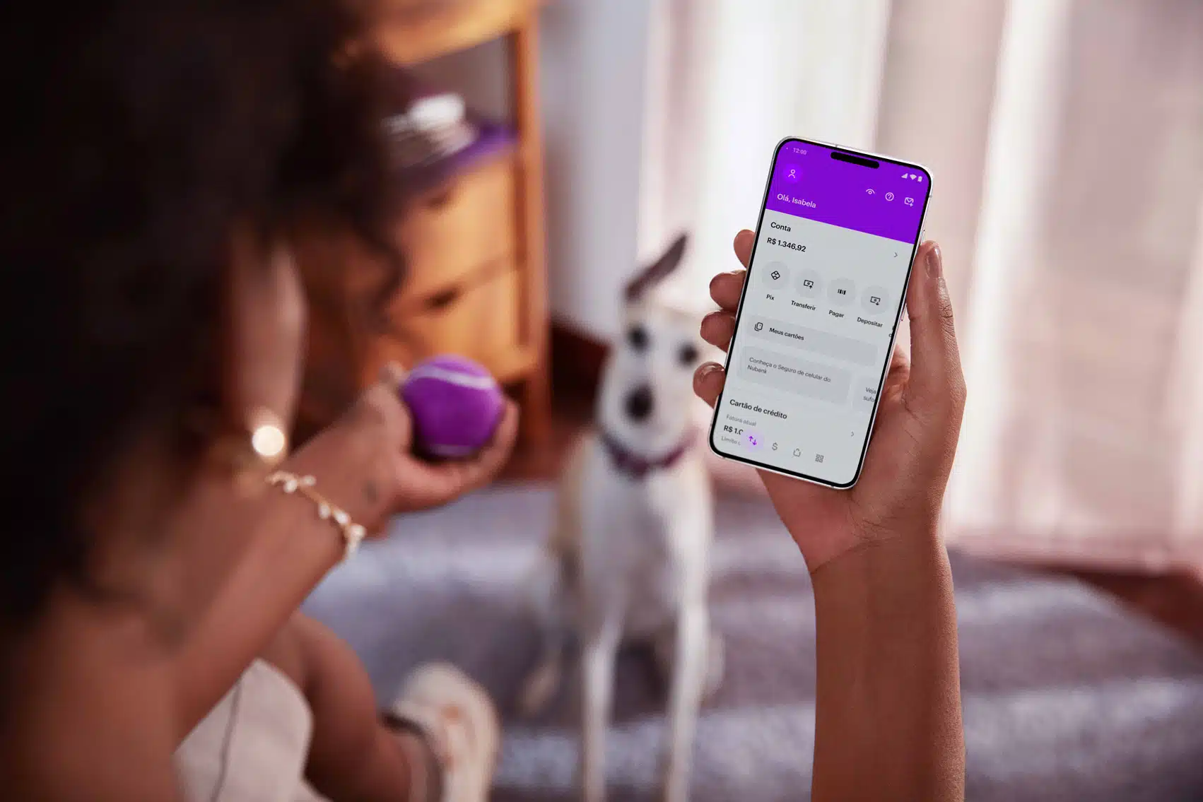 mulher consultando aplicativo nubank no celular no escritorio com seu cachorro